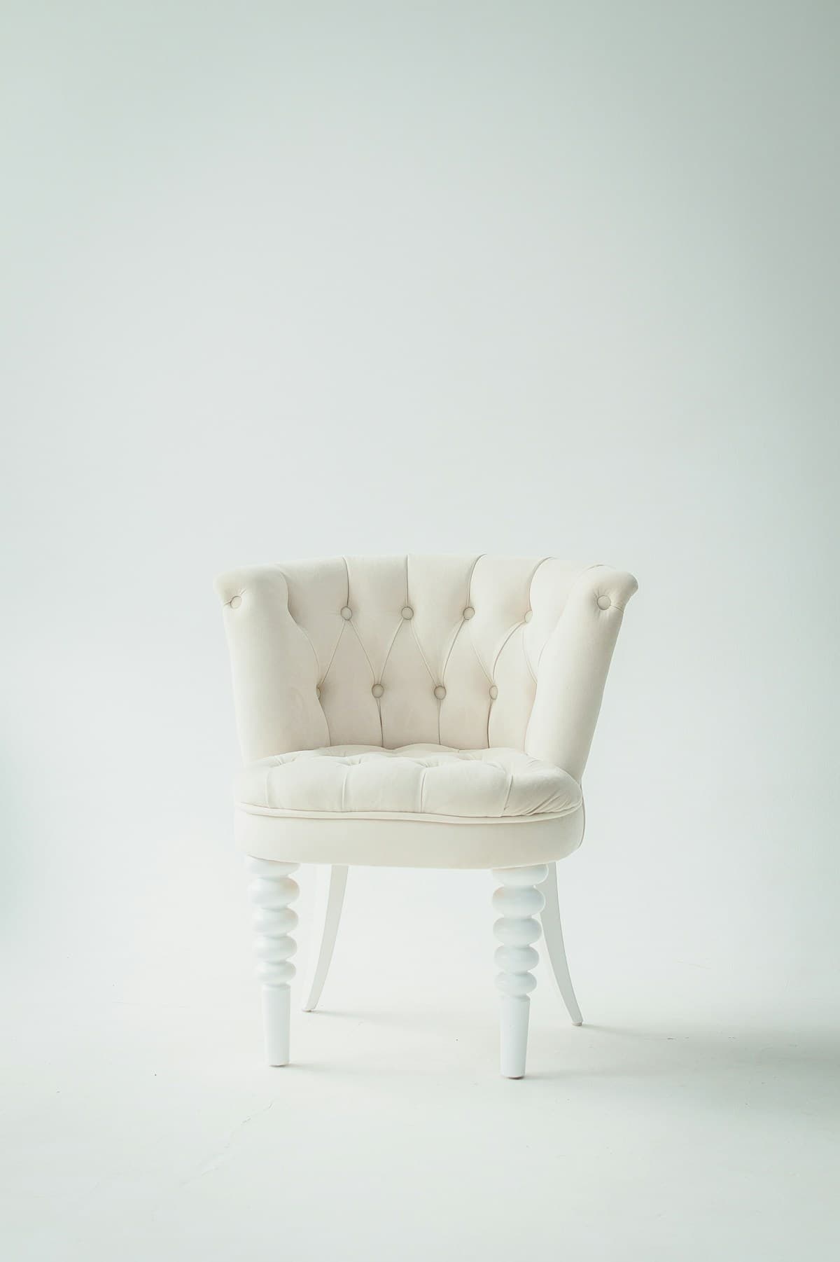 A cream lounge chair against a soft sage backdrop
